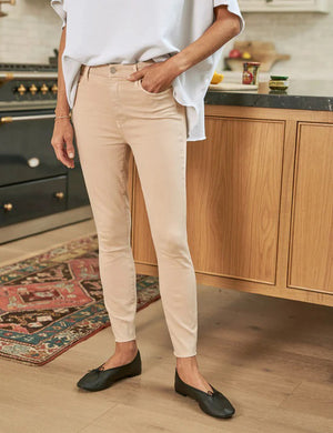 The FRANK & EILEEN SLIGO SKINNY JEAN is a pair of beige, high-waisted skinny jeans crafted from sustainable Italian Performance Denim. They feature a high-rise contour waistband, five pockets, button and zip closure, and a "Frank" label on the waistband. The jeans are displayed against a white textured background.