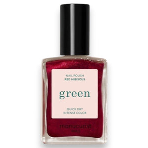 A hand with shiny, iridescent red nails holds a matching bottle labeled “MANUCURIST - GREEN™ NAIL POLISH IN RED HIBISCUS” by MANUCURIST INC against brown skin. This luxurious vegan, cruelty-free nail polish delivers vibrant color and a flawless finish.