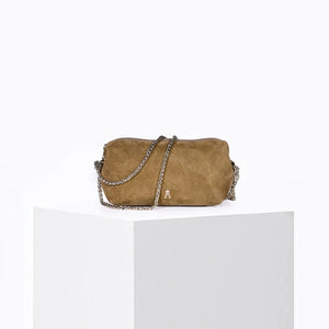 The CRAIE STUDIO - NUAGE SUEDE SEPIA MINI BAG, a compact brown suede shoulder bag featuring a zipper and a long yellow strap, is showcased on a white pedestal against a light background.