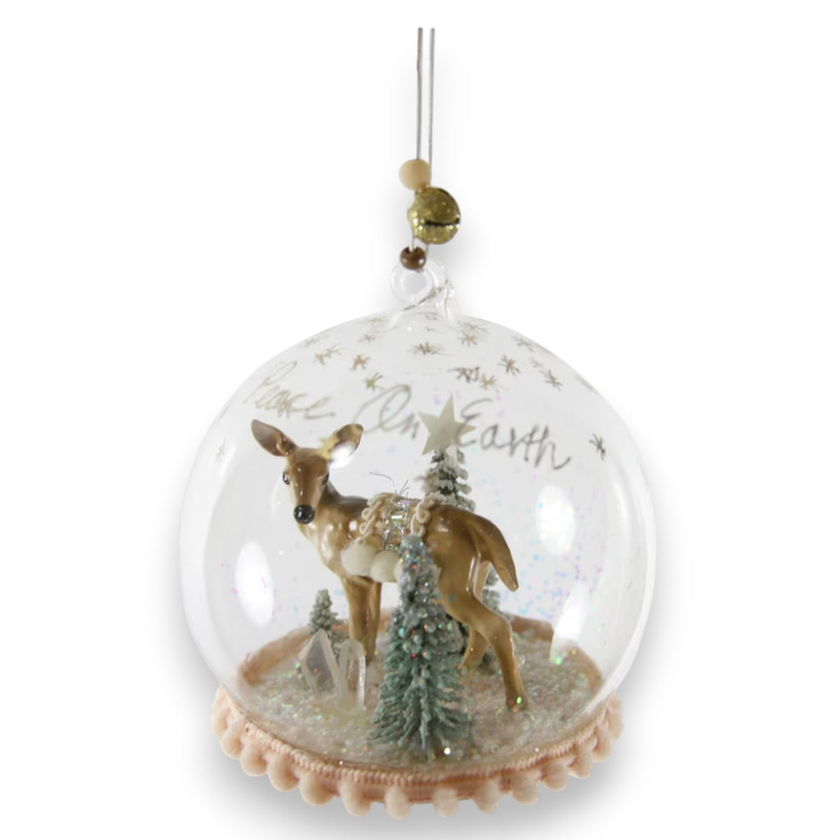 The CODY FOSTER WINTER DEER GLOBE ORNAMENT features a glass dome with a deer, trees, and glitter inside plus &quot;Peace On Earth&quot; text. Hanging by a beaded string, it&#39;s ideal for collectors or as a unique holiday gift.