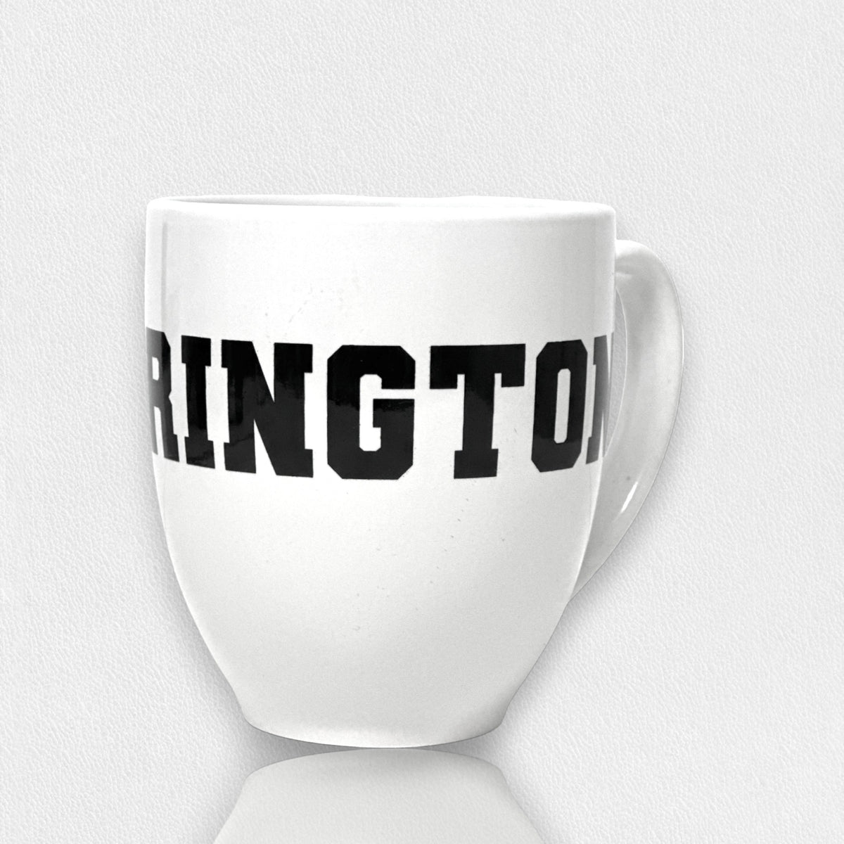 The FEARRINGTON LIFESTYLE COLLECTION - FEARRINGTON MUG by STRAN features the word &quot;FEARLESS&quot; boldly displayed in black, capital letters across its front. Perfect for your morning coffee, this ceramic mug rests on a white surface with a subtle shadow. The clean and minimalistic backdrop highlights its sleek design.