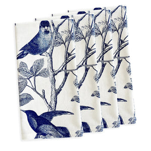 Four white cotton CASKATA - ARBOR BIRDS DINNER NAPKINS by CASKATA, made in India, are neatly stacked and display a repeating pattern of green birds on leafy branches.