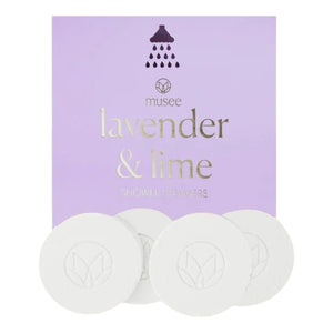 A box of MUSEE - LAVENDER & LIME SHOWER STEAMERS by MUSEE is shown with four round white steamers placed in front. The light purple packaging features gold text and a small shower icon, making it an ideal self-care treat for enhancing any shower routine.