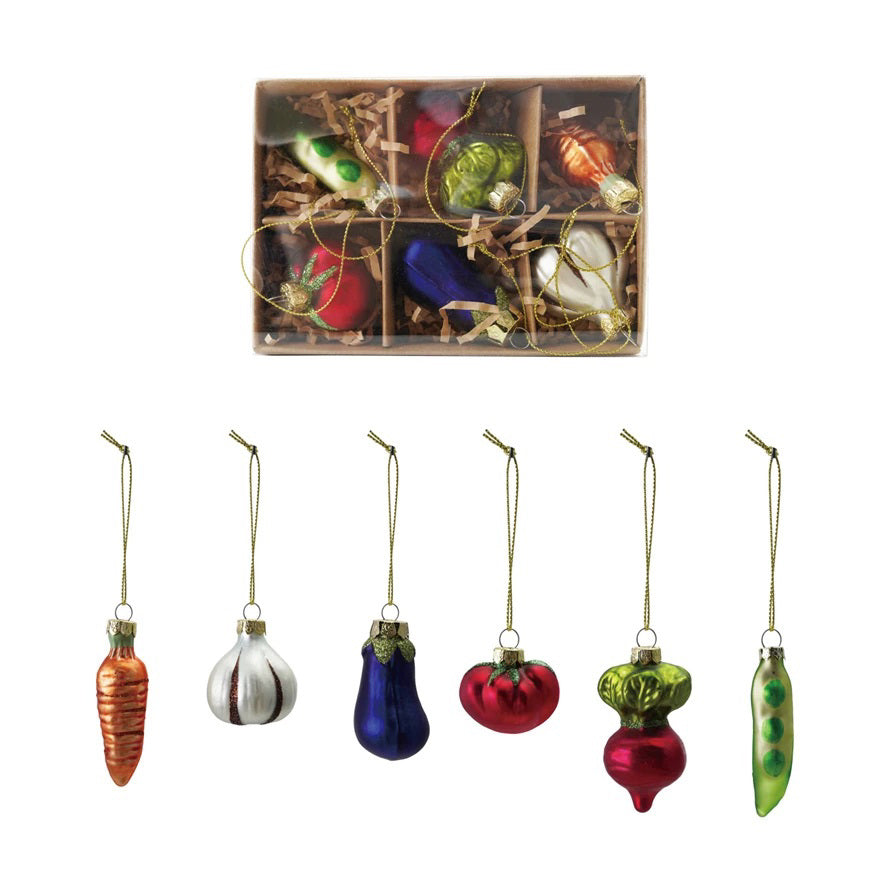 The CREATIVE COOP GLASS VEGETABLE ORNAMENTS set includes six glittery, multicolored glass ornaments—carrot, garlic, eggplant, tomato, radish, and pea pod—with gold hanging strings in a gift box.