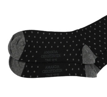 Introducing the AMANDA CHRISTENSEN - TRUE DOT MID-CALF SOCKS IN BLACK: Expertly crafted in Italy, these stylish socks feature a classic black background adorned with small white polka dots. Contrasting gray toes, heels, and cuffs add a distinctive touch, while the premium combed cotton ensures exceptional comfort and timeless elegance.
