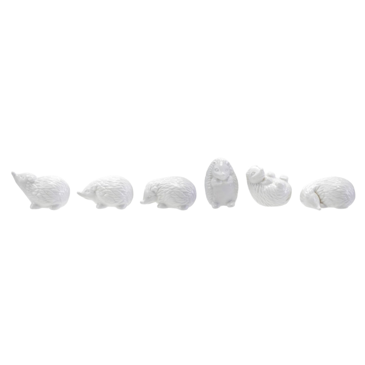 Six CREATIVE COOP WHITE STONEWARE HEDGEHOG figurines in different poses are arranged on and around three whitewashed cylindrical wooden pedestals, perfect for charming farmhouse decor. The background is plain white.