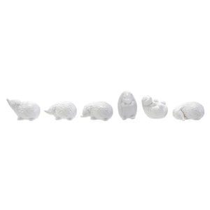 Six CREATIVE COOP WHITE STONEWARE HEDGEHOG figurines in different poses are arranged on and around three whitewashed cylindrical wooden pedestals, perfect for charming farmhouse decor. The background is plain white.