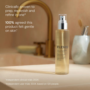 A smiling woman with long gray hair holds a bottle of ELEMIS - PRO-COLLAGEN TONING MIST by ELEMIS - STEINER, a hydrating toning mist formulated to refine the skin. Text on the image reads: “KEY BENEFITS: Preps, Replenishes, Refines.” She is wearing a white tank top and stands against a neutral background.