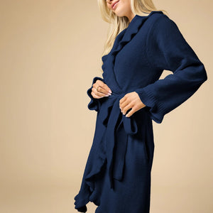 A woman wearing a SOFTIES - RUFFLE CHENILLE ROBE 36″ IN MIDNIGHT, a knee-length navy blue chenille robe with cascading ruffle trim.