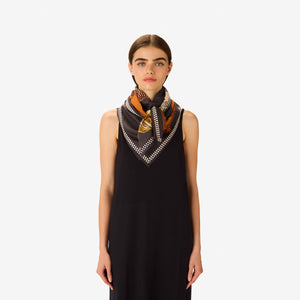 The INOUI EDITIONS - TEQUILA SCARF IN LEMON by INOUI features vibrant cacti and succulents in green, yellow, and white on brown and gray pedestals, set against a dark gray background with a decorative border.