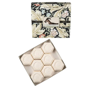 A beautifully designed BAUDELAIRE - GOATS MILK HONEY SOAP 1.4oz Gift Box features eight hexagonal white soaps arranged in an open grid, topped with a floral-patterned lid. These moisturizing BAUDELAIRE soaps are ideal for sensitive skin, providing gentle care with every use.