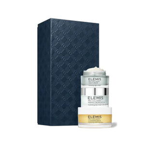 A dark textured rectangular box stands beside three stacked skincare containers labeled "ELEMIS." The ELEMIS - PRO-COLLAGEN HEROES GIFT SET by ELEMIS - STEINER includes a cleansing balm, day cream, and night cream for hydration.