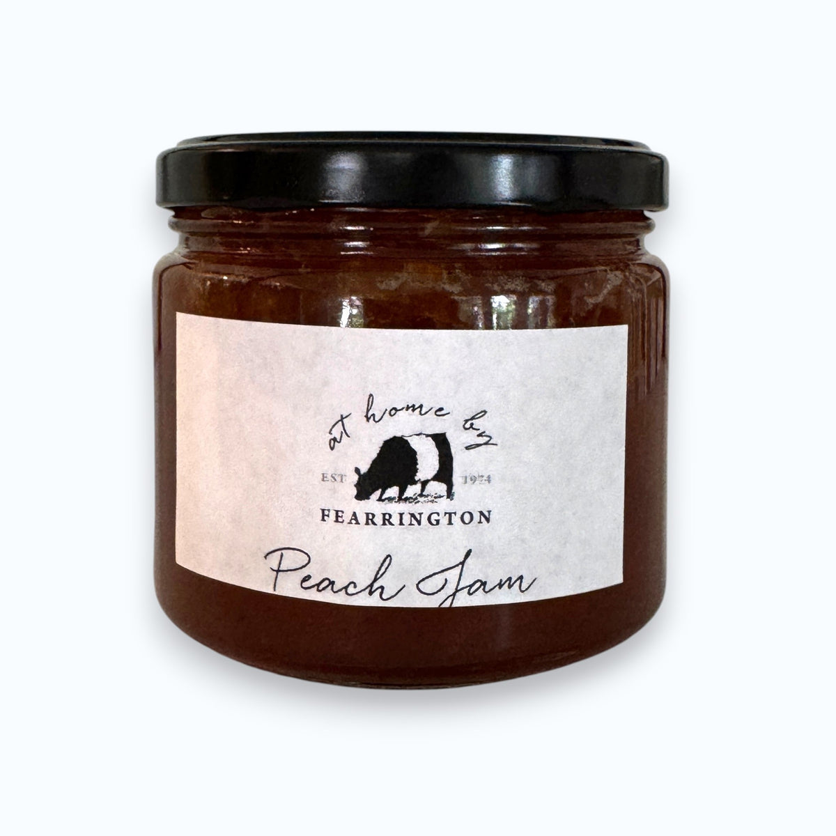 The FEARRINGTON SIGNATURE COLLECTION - FEARRINGTON HOUSEMADE PEACH JAM comes in a glass jar featuring a black lid and is adorned with a black and white striped ribbon. The white label reads "Peach Jam" and lists the ingredients as peach, vanilla, lemon, pectin, and sugar. Perfect as a hostess gift, it also notes that it is handmade by FEARRINGTON HOUSE and may contain allergens.