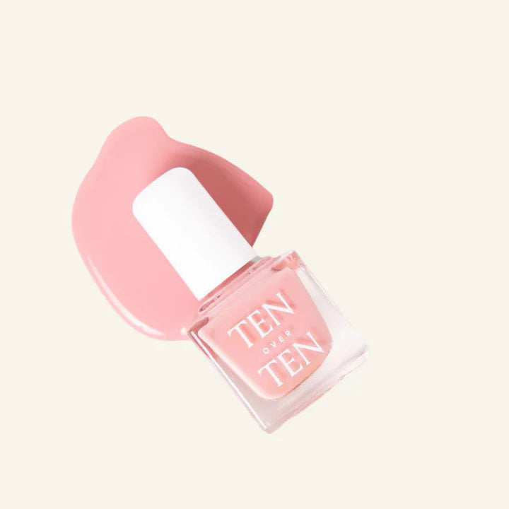 A glass bottle of TENOVERTEN - NAIL POLISH from the brand TEN OVER TEN, featuring a white cap and a dusty pink nail color. The front label displays "TEN OVER TEN" in white uppercase letters. This vegan, eight-free formula ensures both beauty and peace of mind. The background is plain and light-colored.