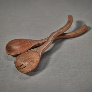 The ZODAX MANGO WOOD CURVY SALAD SERVER SET features two handcrafted servers—a spoon and fork—with a wavy design, crafted from mango wood for elegant dining. Set is displayed on a white background.