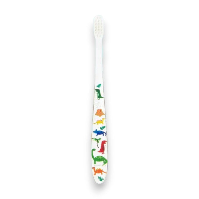 Two HAMICO - KIDS DINO TOOTHBRUSHES by HAMICO/INNOVATIVE TOOTHBRUSH, featuring unique dinosaur designs, sit on a white countertop next to a beige towel. A hint of a green plant is visible in the upper right corner, adding a touch of natural decor to the scene.