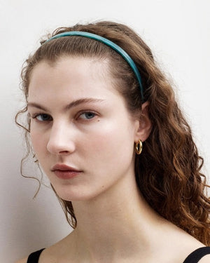 The MACHETE Ultralight Thin Headband in Horn is a slender, curved Italian acetate headband showcasing a marbled pattern in black, gray, cream, and light brown hues. Lightweight and designed for all hair types, it is displayed against a plain white background.