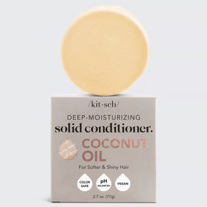 A round, beige solid conditioner bar sits on its light gray packaging labeled "KITSCH Coconut Repair Deep Conditioning Bar Mask." Infused with coconut oil for softness and shine, it detangles and conditions. The package highlights "Color Safe," "pH Balanced," "Vegan," and plastic reduction.