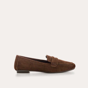 The REQINS HEMA suede loafer in cacao features moccasin-style stitching, a penny strap, and a low black heel for stylish comfort, showcased on a light background.