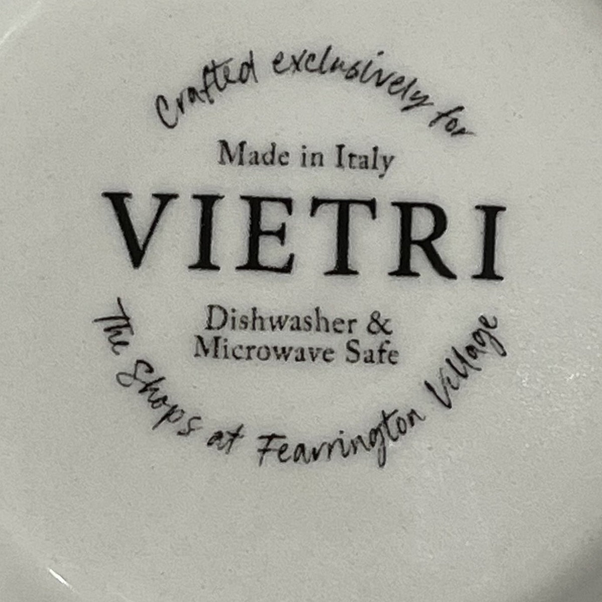 The FEARRINGTON SIGNATURE COLLECTION Beltie Oval Platter by VIETRI features black cow and calf silhouettes on green grass with blue clouds on a cream base, making it a charming gift inspired by Fearrington Village.