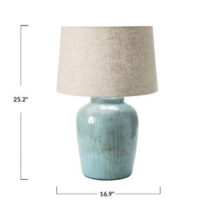 The CREATIVE COOP AQUA STONEWARE LAMP WITH LINEN SHADE features a nature-inspired design with a muted green textured ceramic base and a beige linen shade, set against a white background.