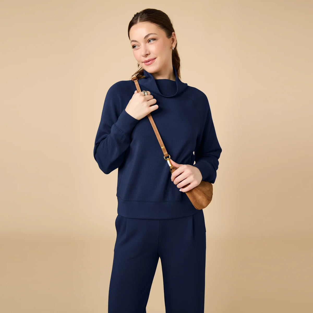 A woman seen from behind wearing the fuchsia SOFTIES - DREAMTECH COWL NECK WITH PLEATED PANT set featuring a long-sleeved cowl neck top and matching pleated pants.