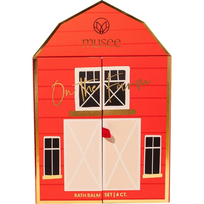 The MUSEE - ON THE FARM BATH BALM SET by MUSEE comes in a charming red, barn-shaped box labeled “musee” that opens to unveil a whimsical farm scene complete with animal figures. The set features four pastel bath balms in blue, yellow, pink, and white—all handcrafted with natural ingredients for a soothing and delightful bath experience.