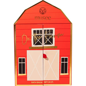 The MUSEE - ON THE FARM BATH BALM SET by MUSEE comes in a charming red, barn-shaped box labeled “musee” that opens to unveil a whimsical farm scene complete with animal figures. The set features four pastel bath balms in blue, yellow, pink, and white—all handcrafted with natural ingredients for a soothing and delightful bath experience.