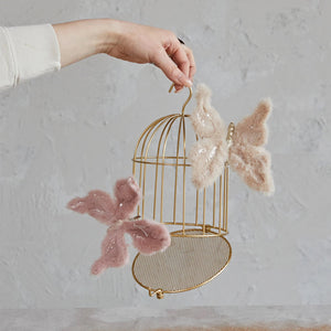 The METAL BIRD CAGE ORN by CREATIVE COOP features a golden finish with vertical bars and a domed top. Designed with a hook for hanging and a small latch-door at the bottom front, this elegant ornament stands gracefully on its base against a plain white backdrop.