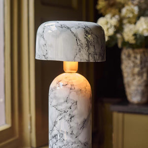 The ABIGAIL AHERN - FAIRFIELD TABLE LAMP features a modern marble effect with a white and gray finish, rounded shade and base, and emits a warm glow—perfect for adding ambient light by the window.