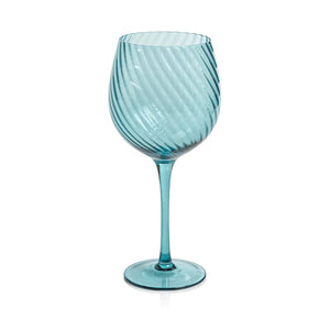 The SAVOY OPTIC SWIRL RED WINE GLASS by ZODAX features a turquoise color with a swirling, ribbed pattern. It boasts a wide bowl, tall stem, and round base, along with a reflective glassy finish. This glass has a capacity of 600 ml.