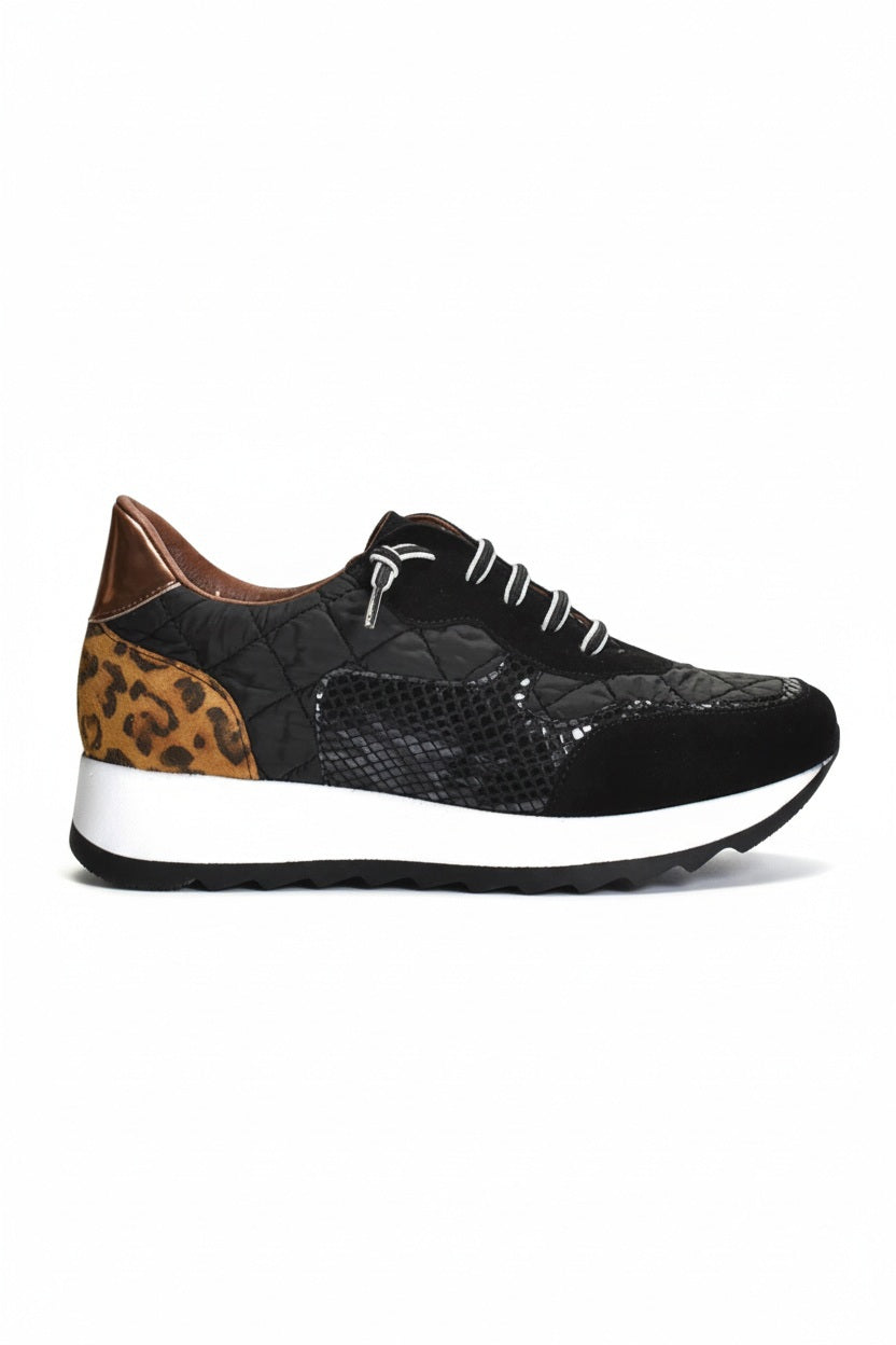 The CORDANI Lizzie Sneaker by CORDANI showcases a stylish leopard print design with brown and tan animal print panels, complemented by black and white laces and finished with a thick white sole featuring a black wavy tread, all set against a plain light background.