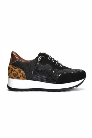 The CORDANI Lizzie Sneaker by CORDANI showcases a stylish leopard print design with brown and tan animal print panels, complemented by black and white laces and finished with a thick white sole featuring a black wavy tread, all set against a plain light background.