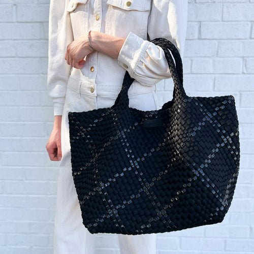 The PARKER &amp; HYDE Oversized Woven Tote Bag is a hand-woven black tote with a matching pouch, both featuring a subtle crisscross pattern. The versatile tote has short handles and a sturdy texture, while the pouch includes a convenient zipper closure.