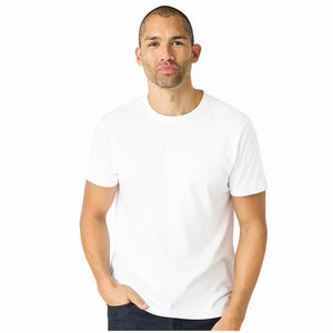 A man with short hair and light stubble wears the MACK WELDON Slub Cotton Crew Neck T-Shirt in Bright White, paired with dark pants, standing against a white background and looking slightly to his left.
