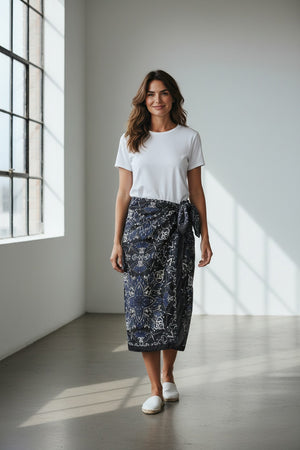 The MAISON LECOMTE - COSTA BRAVA BLACK SARONG by MAISON LECOMTE FLAMENT, featuring a white and blue paisley pattern, is tied in a loose knot against a plain white background.