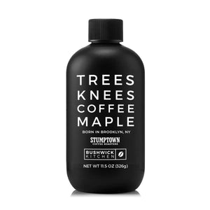 A black bottle labeled “TREES KNEES COFFEE MAPLE” features white text and displays both the Bushwick Kitchen and Stumptown Coffee Roasters logos. With a black cap and 11.5 oz (326g) of gluten-free maple syrup infused with rich coffee flavor, BUSHWICK KITCHEN - ‘TREES KNEES’ COFFEE MAPLE SYRUP makes an excellent addition to any maple syrup gift set.