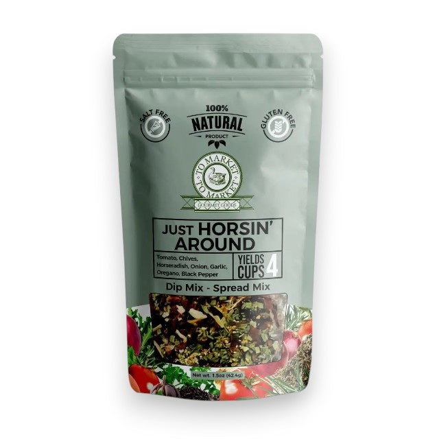 A package of TO MARKET - JUST HORSIN’ AROUND DIP MIX from TO MARKET- DIPS &amp; SPREADS is displayed behind a white bowl of dip accompanied by two crackers. The package highlights zesty ingredients such as horseradish, garlic, and sun-dried tomatoes, and notes that it’s salt-free, gluten-free, and makes 4 cups.