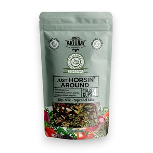 A package of TO MARKET - JUST HORSIN’ AROUND DIP MIX from TO MARKET- DIPS & SPREADS is displayed behind a white bowl of dip accompanied by two crackers. The package highlights zesty ingredients such as horseradish, garlic, and sun-dried tomatoes, and notes that it’s salt-free, gluten-free, and makes 4 cups.
