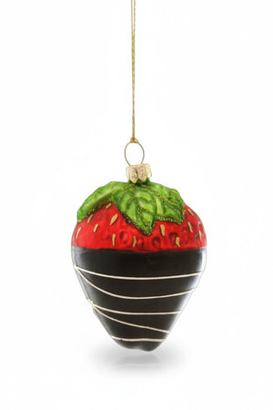 The CHOCOLATE DIPPED STRAWBERRY ORNAMENT by CODY FOSTER features a glass strawberry dipped in chocolate with white stripes and green leaves, hanging by a gold string—an ideal festive treat for dessert lovers.