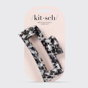 The KITSCH - Eco Friendly Jumbo Open Shape Claw Clip in Black is a rectangular hair accessory featuring a marbled black and white pattern, cutout center, and curved edges. Made from recycled materials, it is displayed on a light gray background.