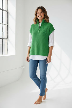 A woman wears the HINSON WU - BROOKE SLEEVELESS KNIT VEST in bright green over a white long-sleeve shirt and blue jeans, standing against a plain light background.