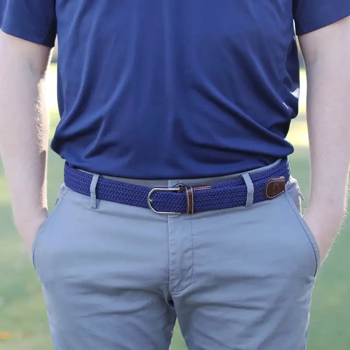 The ROOSTAS - PEEBLE BEACH WOVEN STRETCH BELT by ROOSTAS features a navy braided design with brown leather ends and a silver adjustable clasp, shown coiled on a white background.