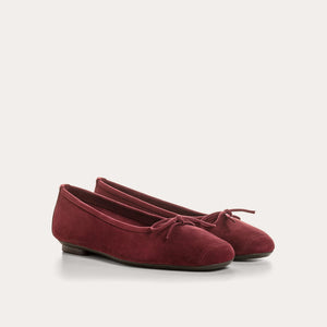 The REQINS - HARMONY Suede Ballerina Flats in Bordeaux, featuring elegant small bows on the toes, are displayed on a plain light background.