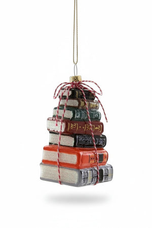 A 3.5-inch GLASS STACKED BOOKS ORNAMENT by Cody Foster, shaped like a stack of six colorful books tied together with red and white baker’s twine.