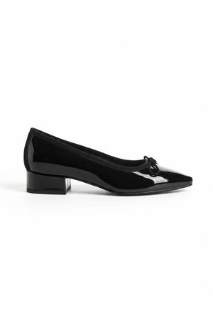 The REQINS FETICHE heeled ballerina shoe features black patent leather, a rounded toe, small bow detail, and a block heel, shown on a plain white background.