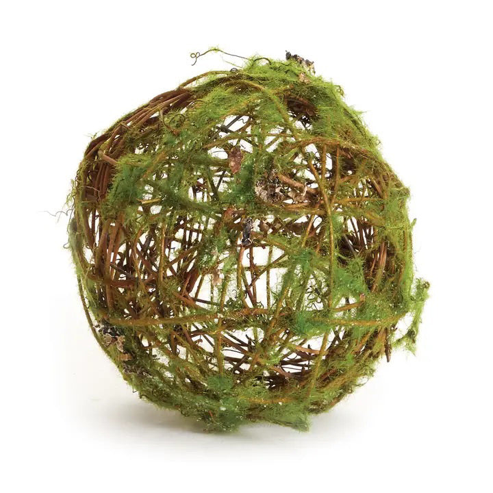 The MOSSY WRAPPED TWIG ORB 6" from NAPA HOME AND GARDEN is a spherical decorative piece crafted from intertwining brown twigs partially adorned with green moss. These orbs exude an organic and rustic aesthetic, providing a natural texture and whimsical charm that make them perfect for interior use only.