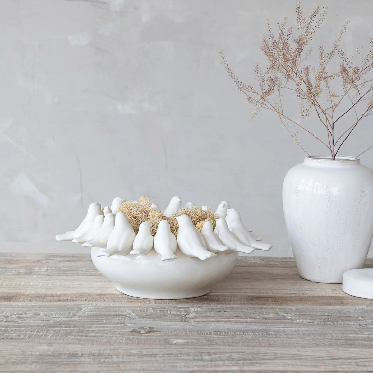 The CREATIVE COOP DECORATIVE STONEWARE BOWL WITH BIRDS ON RIM features charming bird figurines perched along the edge—a lovely accent for farmhouse decor. One bowl is seen from above, the other from the side, highlighting its three-dimensional details.