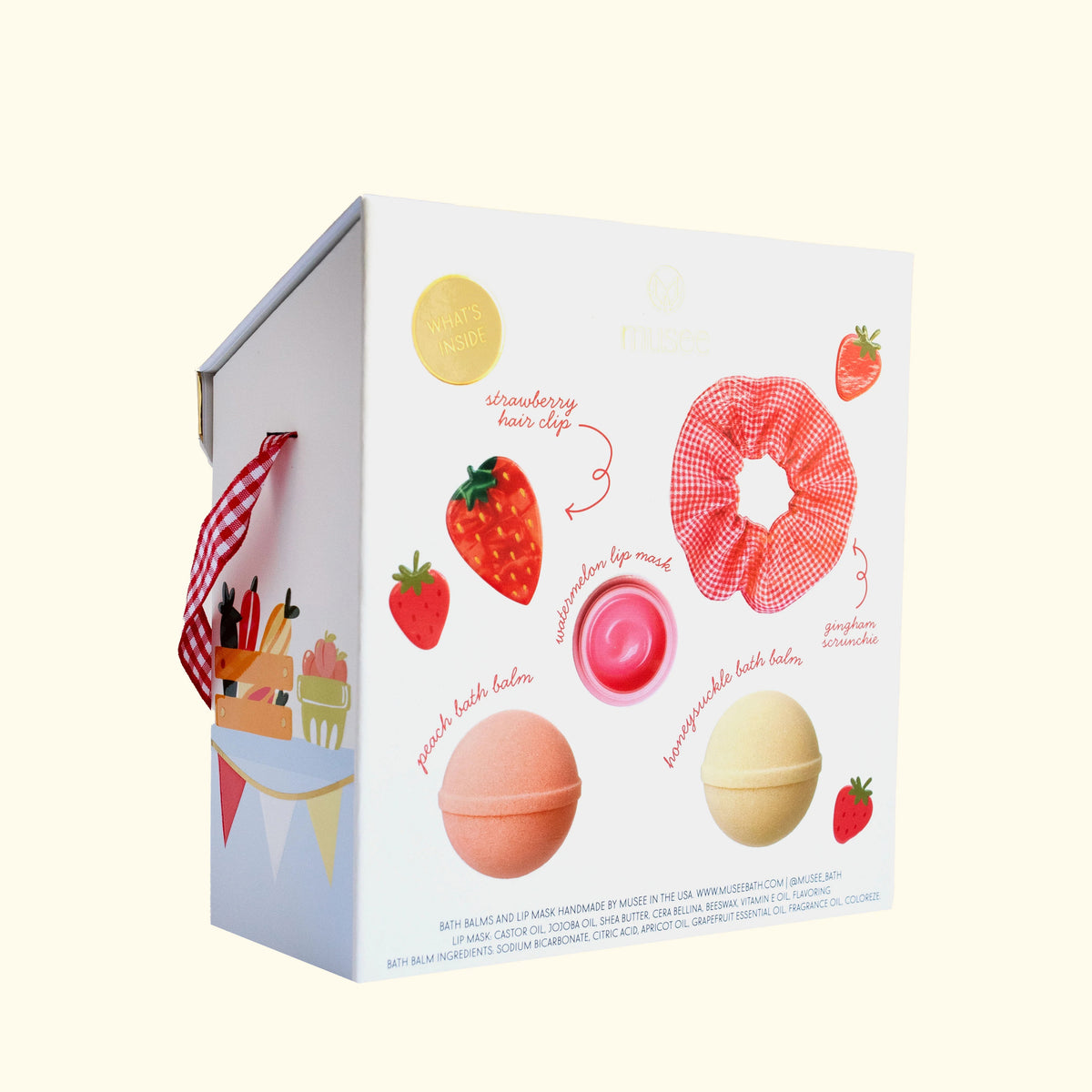 MUSEE - FARMERS’ MARKET GIFT SET by MUSEE features two soothing bath balms, a pink hair clip, a hydrating lip mask, and a red gingham scrunchie—all beautifully packaged in a decorative box adorned with checkered trim and delightful fruit illustrations.