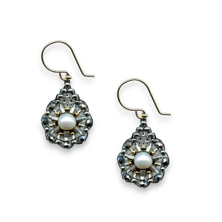 The MIGUEL ASES - PYRITE SILVER RONDELLE DROP EARRING by MIGUEL ASES, INC. showcases a central white pearl encircled by detailed silver and gold craftsmanship. Handcrafted in America, these earrings feature an elegant design that incorporates small silver beads, 14K gold-fill accents, and a looped gold hook for wearing.